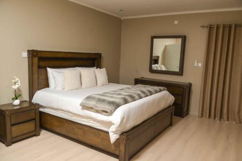 a bedroom with a large bed and a mirror at Immaculate Villa in Gaborone