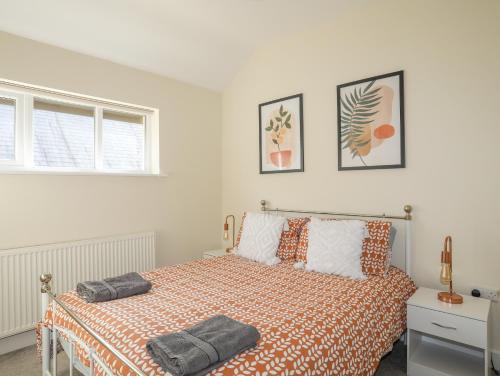a bedroom with a bed with an orange and white bedspread at Maenan in Criccieth
