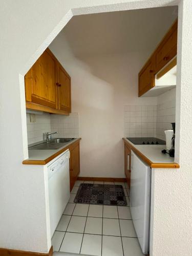 a small kitchen with wooden cabinets and a sink at LA TANIA COURCHEVEL 73120 in Courchevel