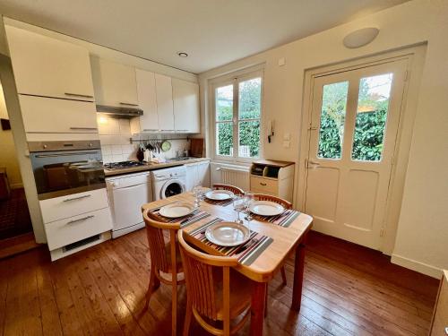 une cuisine avec une table en bois et des chaises ainsi qu'une salle à manger dans l'établissement L'Annexe Apparthôtel du 8, 3 étoiles, à Besançon