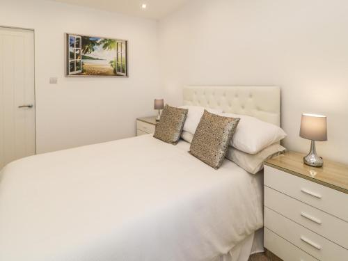 a bedroom with a white bed and a dresser at Top Of The Lane Luxury Holiday Apartment in Benllech