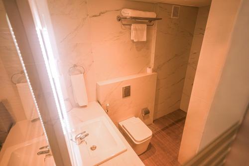 a white bathroom with a toilet and a sink at Casa D'or Hotel in Beirut