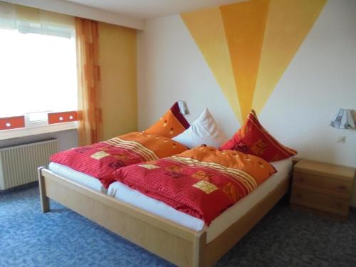 1 dormitorio con 1 cama con almohadas de color rojo y naranja en Ferienhaus Bauer mit wunderschönem Panoramablick, en Tännesberg