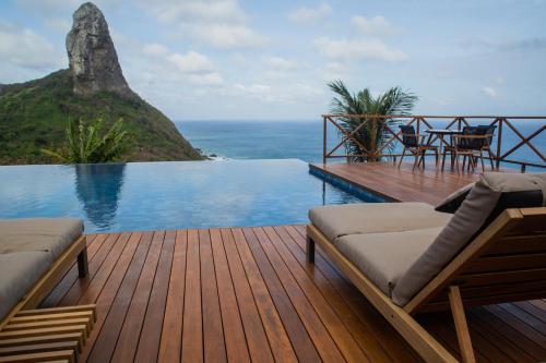 a wooden deck with chairs and a swimming pool at Pousada Ecológica Akanã in Fernando de Noronha