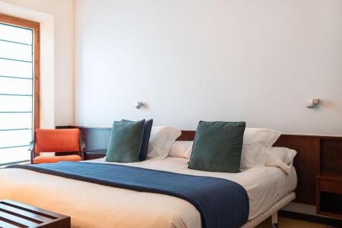 a bedroom with a bed with two green pillows at Hotel Emporda in Figueres
