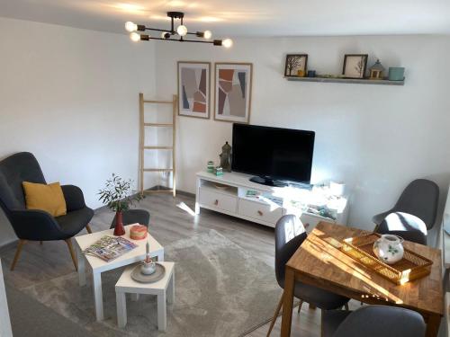 sala de estar con TV, mesa y sillas en Ferienhaus Naturblick, en Bad Frankenhausen