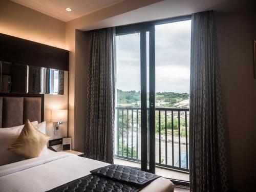 a bedroom with a bed and a large window at Eastern Gate - A Bergamont Group of Hotel in Port Blair
