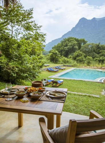 a wooden table with food on it next to a pool at Gal Oya Lodge in Galgamuwa