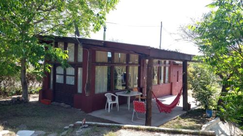 a small red house with a table and a hammock at Cabaña en Villa General Belgrano in Villa General Belgrano