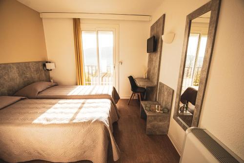 a hotel room with a bed and a mirror at Hôtel le Panoramic - Votre Hôtel au cœur des Gorges du Verdon in La Palud sur Verdon