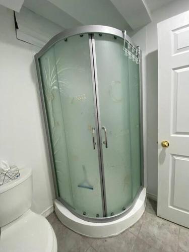 La salle de bains est pourvue d'une douche en verre et de toilettes. dans l'établissement Adorable Quiet Open Concept Private Studio Suite, à Ajax