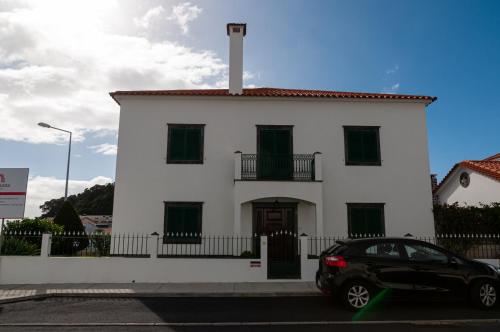 a black car parked in front of a white building at Pico do Moinho House in Fajã de Baixo