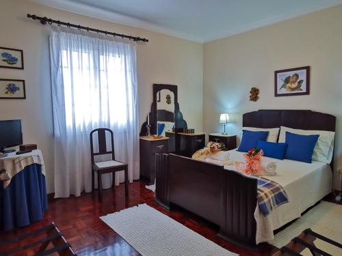 a bedroom with a large bed with blue pillows at Pico do Moinho House in Fajã de Baixo