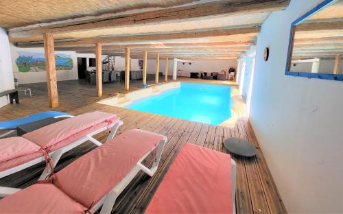 una piscina en una casa con sillas rojas en Grande maison familiale avec piscine couverte, en Lespignan