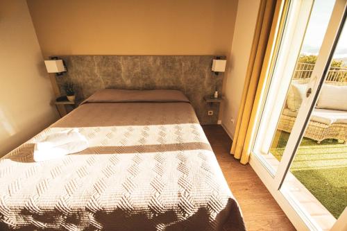 a small bedroom with a bed and a window at Hôtel le Panoramic - Votre Hôtel au cœur des Gorges du Verdon in La Palud sur Verdon