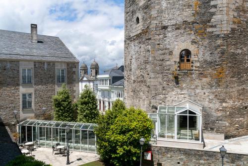 a building with a glass greenhouse next to a castle at Parador de Vilalba in Villalba