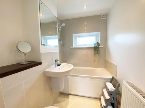 un bagno bianco con lavandino e vasca di 18 Coastline apartment a Newquay
