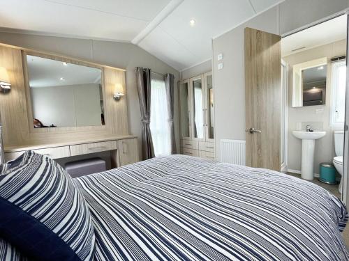 1 dormitorio con cama, lavabo y espejo en 11 Porth Valley Retreat, en Newquay Bay Resort