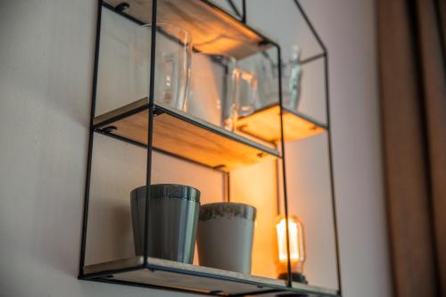 a glass shelf with vases in front of a mirror at Bed & Bos de 14 Sterren in Den Burg