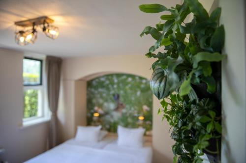 a bedroom with a bed and a plant on the wall at Bed & Bos de 14 Sterren in Den Burg
