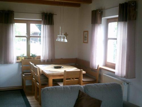 uma sala de jantar com mesa, cadeiras e janelas em Ferienwohnung Familie Köck em Mauth