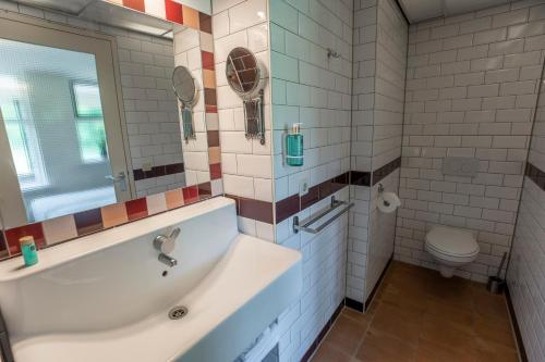 a bathroom with a tub and a toilet at Bed & Bos de 14 Sterren in Den Burg