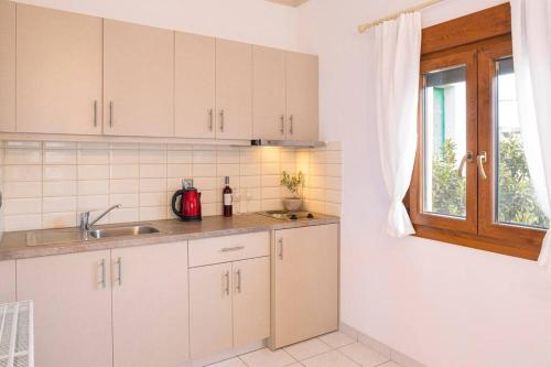 uma cozinha com armários brancos, um lavatório e uma janela em Green Studio in Kantouni em Kokkari