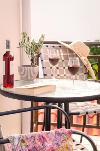 a table with two glasses of wine on a balcony at Green Studio in Kantouni in Kokkari