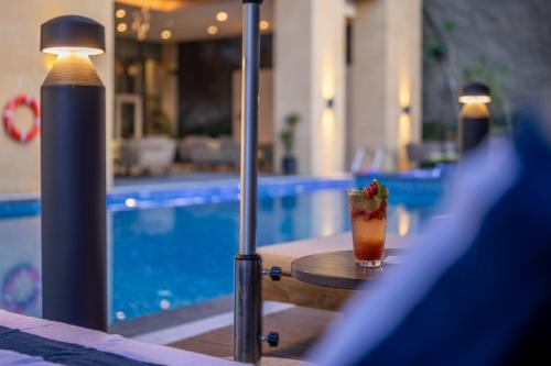 a drink sitting on a table next to a swimming pool at Citadines Abha in Abha