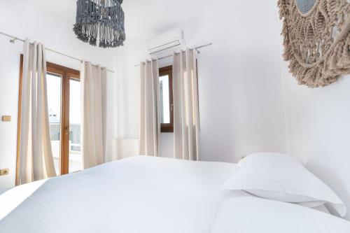 a white bedroom with a white bed and a window at Zoe & Zen Collection in Kampos Paros
