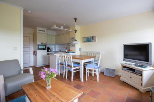 a living room with a table and a kitchen at Hardesweg 63 Nummer 2 in Wrixum