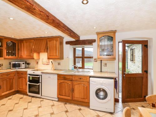 a kitchen with wooden cabinets and a washer and dryer at The Stable in Craven Arms
