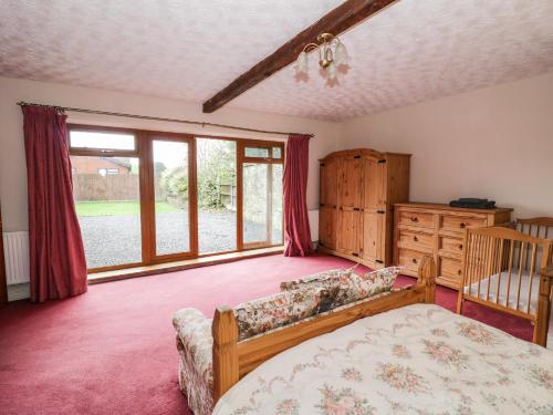 a bedroom with a bed and a couch and windows at The Stable in Craven Arms