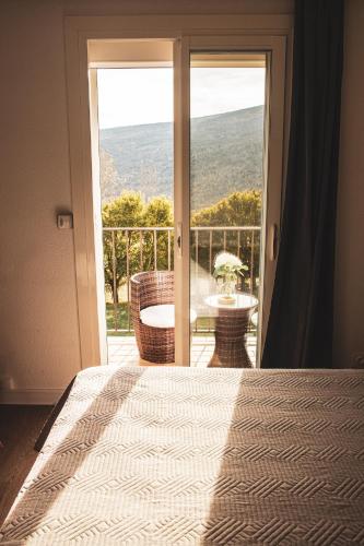 a bedroom with a bed and a view of a balcony at Hôtel le Panoramic - Votre Hôtel au cœur des Gorges du Verdon in La Palud sur Verdon