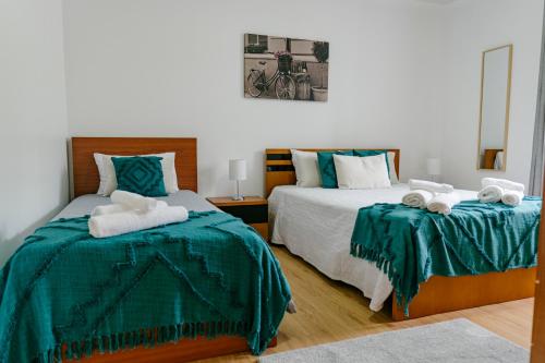 ein Schlafzimmer mit zwei Betten mit grüner Bettwäsche und Handtüchern in der Unterkunft Village House in Ribeira Grande