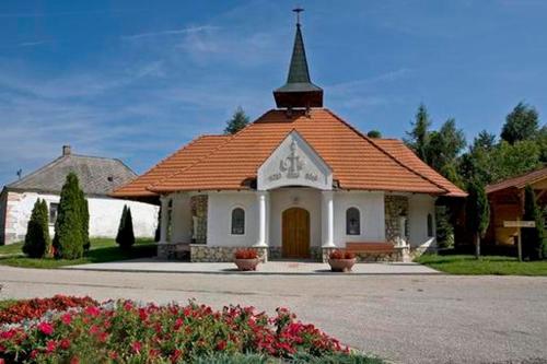 uma pequena igreja com um telhado laranja e um campanário em Harmónia Vendégház em Németbánya