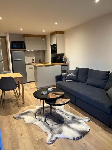 un salon avec un canapé bleu et une table dans l'établissement Appart au centre de la station, entièrement rénové, , parking privé et wifi gratuit, à Les Deux Alpes