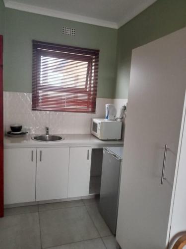 a kitchen with a sink and a microwave at Emampingeni lodge in Bizana