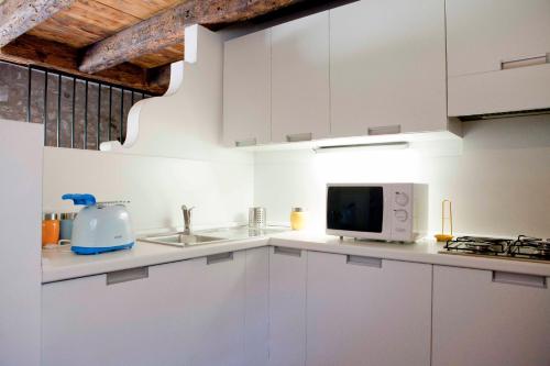 a white kitchen with a microwave and a sink at Ca' Marisa Aquileia in Aquiléia