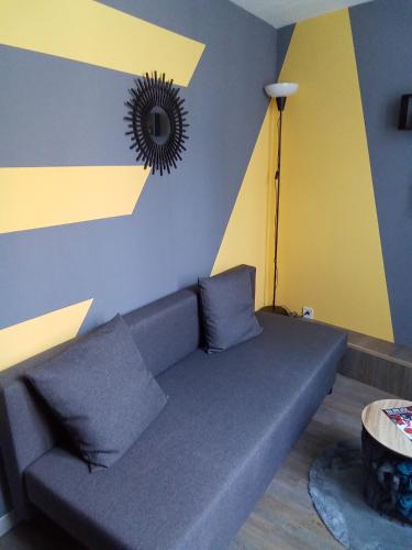 um sofá num quarto com uma parede amarela e azul em Cosy em Marselha