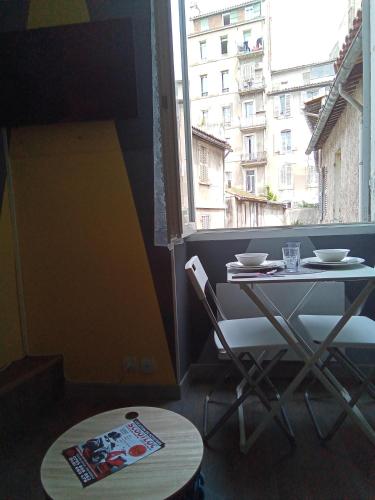 une table et des chaises dans une pièce avec une fenêtre dans l'établissement Cosy, à Marseille