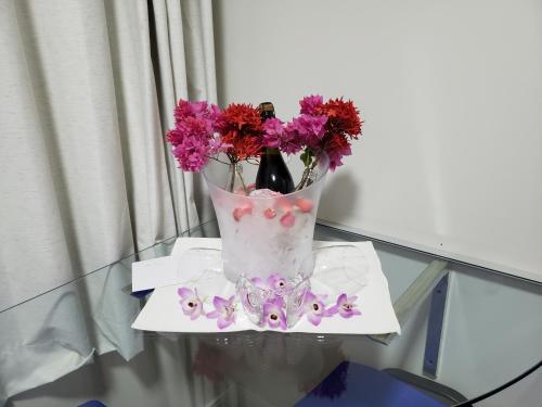 a vase with pink flowers on a glass table at Pousada Cateto - Zona Rural in Capitólio