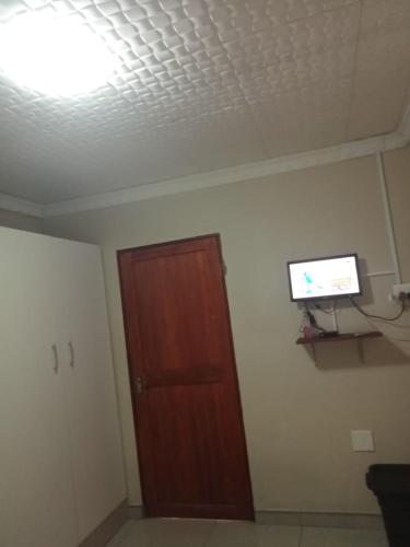 a room with a door and a television on the wall at Emampingeni lodge in Bizana