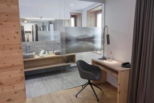a desk and a chair in a bathroom with a sink at Hotel Baer & Post Zernez in Zernez
