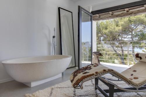 a bathroom with a tub and a chair and a window at Magical Ibizan Villa Walking Distance To The Beach Es Vedra Style 6 Bedrooms Fabulous Sea Views San Jose in Sant Josep de Sa Talaia