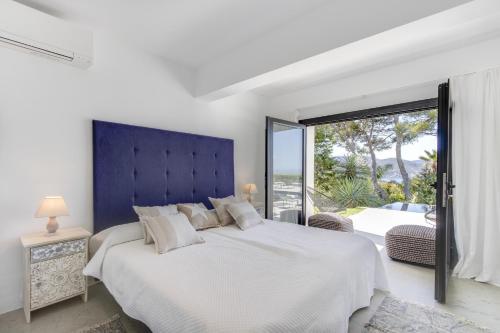 サン・ジョセップ・デ・サ・タライアにあるMagical Ibizan Villa Walking Distance To The Beach Es Vedre Style 6 Bedrooms Fabulous Sea Views San Joseの白いベッドルーム(大型ベッド1台、大きな窓付)