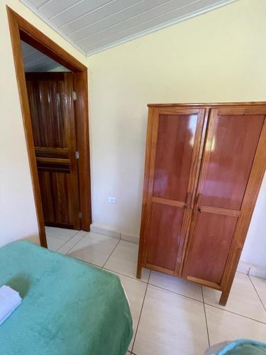 a bedroom with a bed and a wooden cabinet at Sítio Chalako, casa exclusiva às margens do Rio Mimoso in Bonito