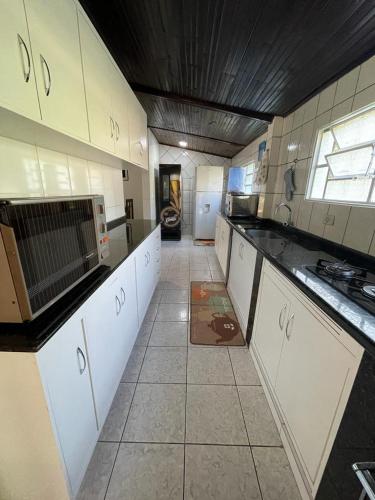 a large kitchen with white cabinets and a window at Sítio Chalako, casa exclusiva às margens do Rio Mimoso in Bonito