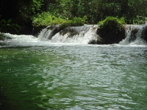a waterfall in front of a body of water at Sítio Chalako, casa exclusiva às margens do Rio Mimoso in Bonito