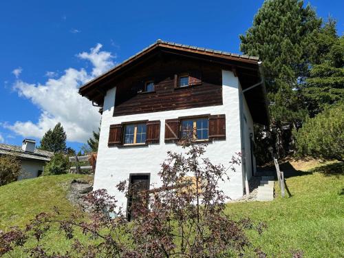 a white house with a wooden roof on a hill at Haus Maran in Urmein